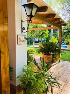 a pergola with plants and a sign for a house at B&B Casa Adelante Sevilla in Espartinas