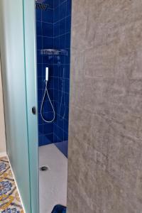 a bathroom with a shower with a blue tiled wall at Cave Bianche Apartments in Favignana