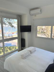 1 dormitorio con 1 cama blanca y 2 ventanas en Espectacular departamento sobre la laguna para parejas en Chascomús