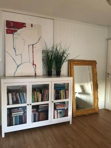 ein weißes Bücherregal mit Büchern und einem Spiegel in der Unterkunft Stort hus i Porsgrunn sentrum med raskt, pålitelig internett og gratis parkering in Porsgrunn