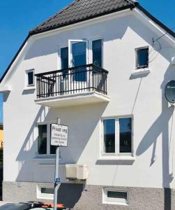 um edifício branco com uma varanda e um sinal em frente em Stort hus i Porsgrunn sentrum med raskt, pålitelig internett og gratis parkering em Porsgrunn