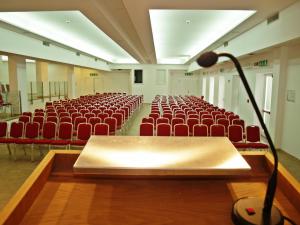uma sala de conferências vazia com cadeiras vermelhas e um microfone em Club Esse Roccaruja em Stintino