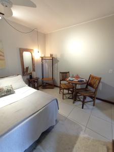 a bedroom with a bed and a table and chairs at Casa da lu Itacoatiara -Suíte Andorinhas in Niterói