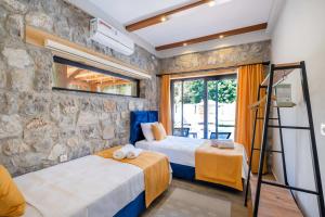 two beds in a room with a stone wall at Müstakil havuzlu jakuzili tatil villası in Fethiye