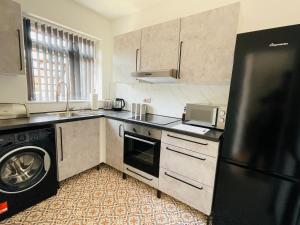 uma cozinha com um frigorífico preto e uma máquina de lavar louça em Lovely 2 bed Apartment, Arnold Town centre. em Nottingham