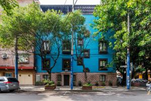 un edificio azul con árboles delante de él en Condesa Square by RentinBA en Ciudad de México