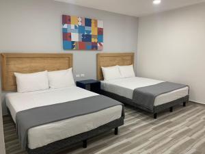 a room with two beds and a painting on the wall at Capital Hotel Saltillo in Saltillo