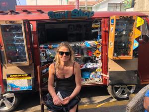 a woman sitting in front of a surf shop at Surf hostel My Friends in Huanchaco