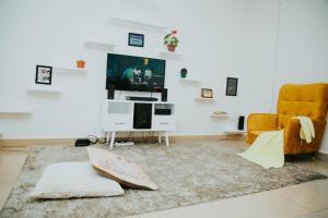 uma sala de estar com uma televisão, uma cadeira e um tapete em Winnie's Cozy Home em Iringa