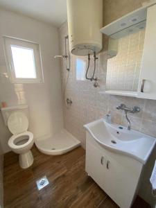 a white bathroom with a toilet and a sink at Apartman MARA in Šestanovac +7 photos