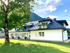 a white house with a black roof and a tree at Obstgarten Gästehaus in Hollenstein an der Ybbs