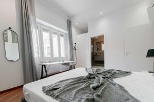 a white bedroom with a bed with a blanket at Realkasa Amendola Apartment in Bologna