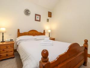 Un dormitorio con una gran cama de madera con sábanas blancas. en The Hayloft en Keswick