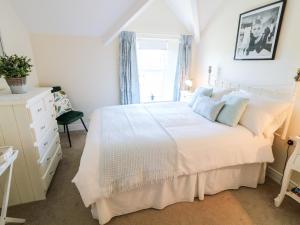 a bedroom with a white bed and a window at 4 The Cloisters in Bushmills