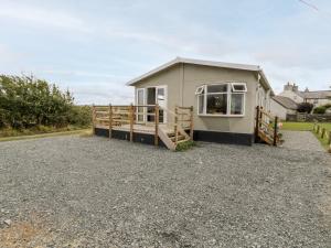 a small house with a fence and a gravel driveway at Porthwen Lodge in Amlwch