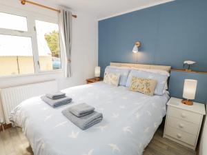 a bedroom with a large white bed with towels on it at Porthwen Lodge in Amlwch