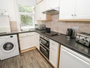 a kitchen with white cabinets and a washer and dryer at Amlwch in Llandudno