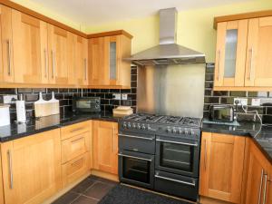 a kitchen with wooden cabinets and a stove top oven at 11 Bro Celyn in Holyhead