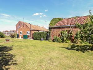 een tuin met twee bakstenen huizen en een grasveld bij Poppy Cottage in Sleaford