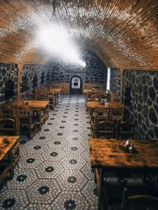 een restaurant met houten tafels en stoelen en een plafond bij Zangezur Hotel in Goris