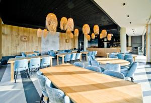un restaurante con mesas de madera y sillas azules en Aqua Resort Apartments - Pool & Sauna, Aqua Park en Kołobrzeg