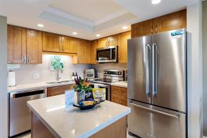 a kitchen with wooden cabinets and a stainless steel refrigerator at Maui Banyan H311 1BD 2BA 3 min walk to the beach in the Heart of South Kihei! in Wailea