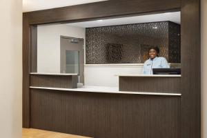 a woman is standing at a reception desk in a room at Candlewood Suites Charleston-Northwoods, an IHG Hotel in Charleston