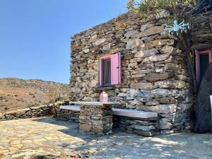ein Steingebäude mit einer Bank und einer rosa Tür in der Unterkunft OWL’S NEST/THE PINK COTTAGE in Ioulis