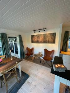 a living room with chairs and a wooden floor at Hyggelig sommerhus. med udsigt, til vand fra senge in Veksø