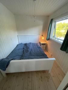 a bed in a small room with a window at Hyggelig sommerhus. med udsigt, til vand fra senge in Veksø