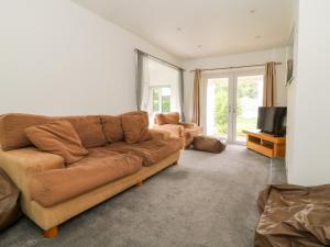 uma sala de estar com um sofá castanho e uma televisão em Inglenook em Ripon