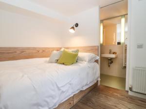 a bedroom with a large white bed with yellow pillows at Apple Cottage in Cheltenham