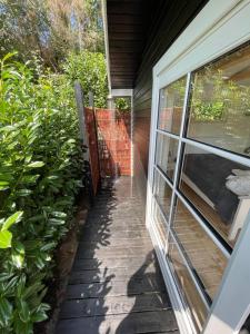 a walkway next to a house with a window at Hyggelig sommerhus. med udsigt, til vand fra senge in Veksø