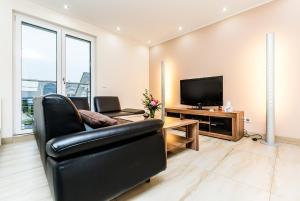 a living room with a black leather chair and a television at Komfort Design Wohnung Köln in Cologne