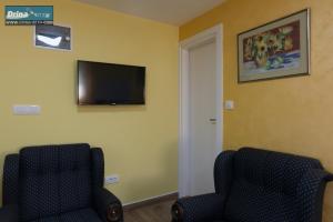 een kamer met 2 stoelen en een televisie aan de muur bij Apartman Raj Macevine in Bajina Bašta