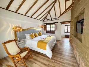 ein Schlafzimmer mit einem Bett, einem Stuhl und einem TV in der Unterkunft Hotel Boutique El Carmel in Villa de Leyva