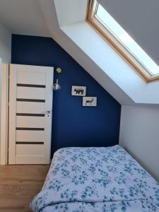 a blue bedroom with a bed and a skylight at Apartamenty Nowickiego in Lublin