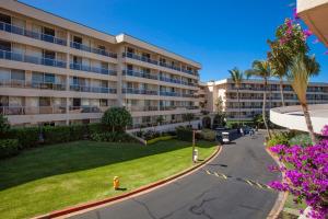 an apartment building with a park in front of it at Maui Banyan H311 1BD 2BA 3 min walk to the beach in the Heart of South Kihei! in Wailea
