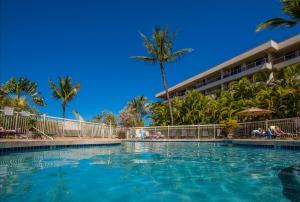a swimming pool in front of a resort with palm trees at Maui Banyan H311 1BD 2BA 3 min walk to the beach in the Heart of South Kihei! in Wailea