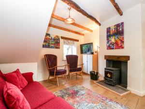a living room with a red couch and a fireplace at Tinmans Cottage in Lydbrook
