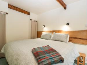 a bedroom with a bed with a blanket on it at Tinmans Cottage in Lydbrook