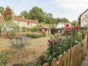 a garden with a fence and a table and flowers at Tinmans Cottage in Lydbrook