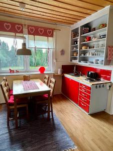 a kitchen with red cabinets and a table with chairs at ,,Björklunda" cozy apartment in swedish lapland in Lycksele