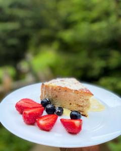 ein Stück Kuchen auf einem Teller mit Erdbeeren und Blaubeeren in der Unterkunft Садиба Одеса in Podobovets