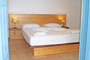 a bedroom with a bed with white sheets and two lamps at St George Village in Batsi