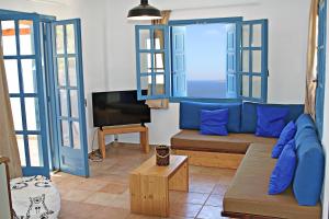 un salon avec un canapé bleu et une télévision dans l'établissement St George Village, à Batsi