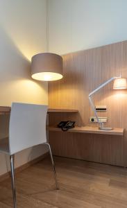 a white chair and a lamp in a room at Hotel Checkin Valencia Ciscar in Picanya