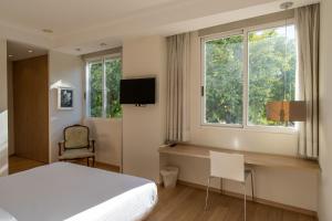 1 dormitorio con cama, escritorio y ventana en Hotel Checkin Valencia Ciscar, en Picaña