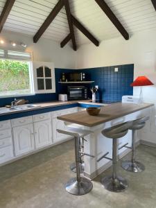 una cocina con armarios blancos y una mesa con taburetes en Habitation Loumavi en Sainte-Rose