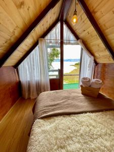 Bett in einem Zimmer mit einem großen Fenster in der Unterkunft La Puerta Del Lago ECOPARQUE in Tota